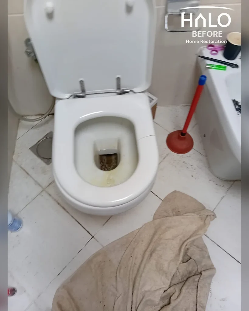 Before a home restoration deep clean in Ras Al Khaimah - heavily stained toilet bowl in a cluttered, untidy bathroom