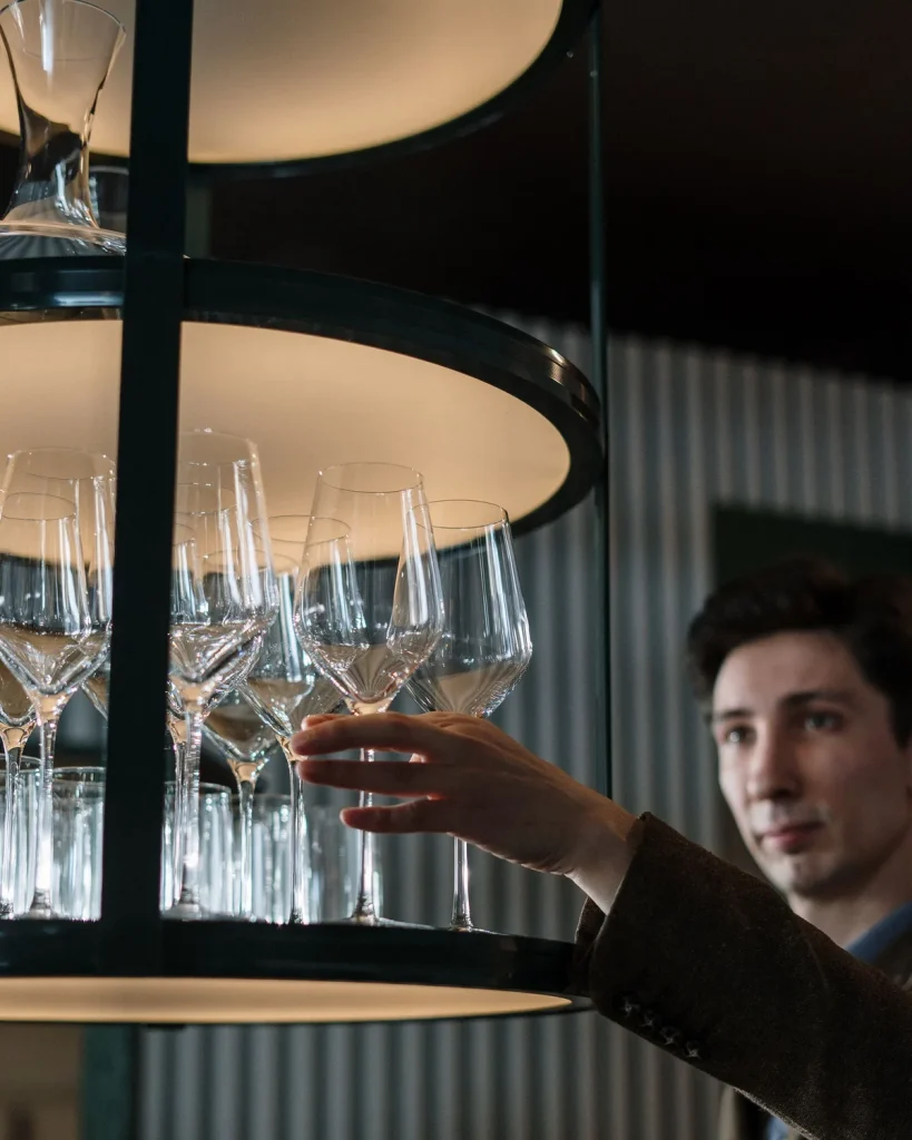 Clean wine glasses lined up on a lit rack in a Ras Al Khaimah bar, washed and dried without hand polishing