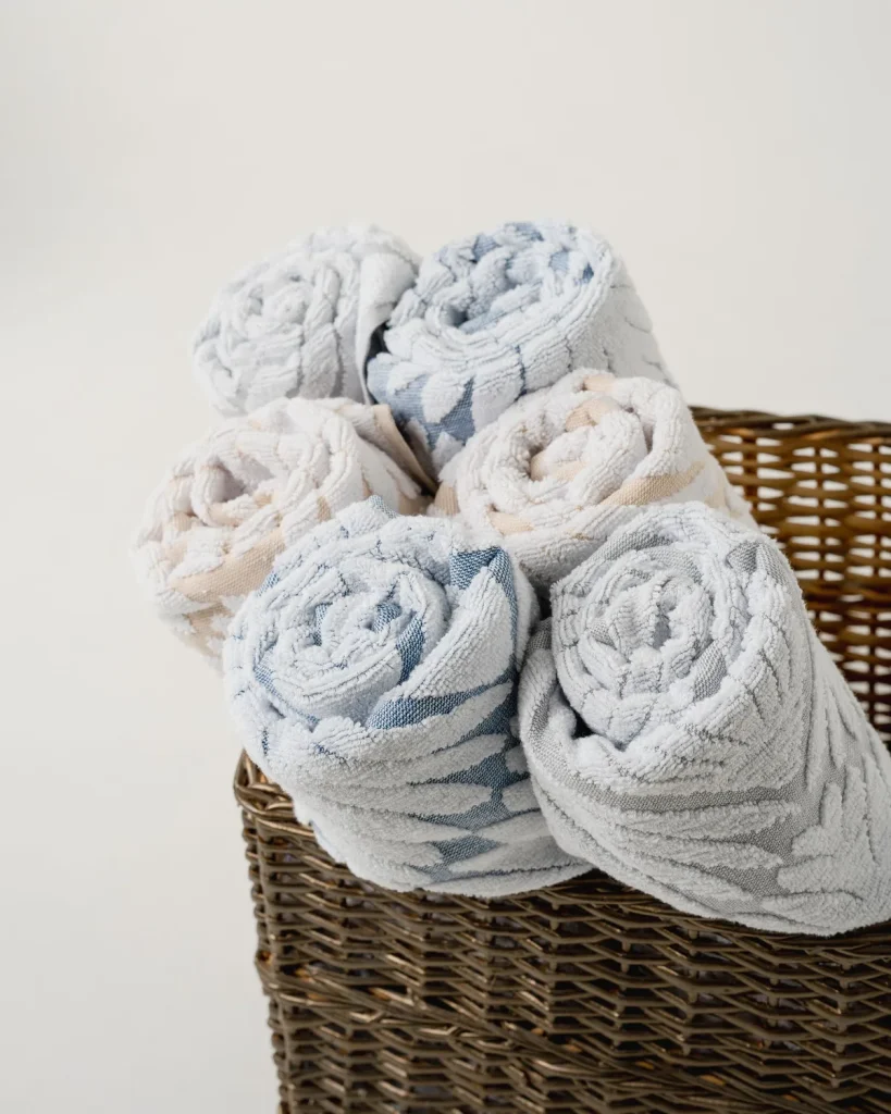Rolled clean towels stacked in a wicker laundry basket, ready for delivery back to a Ras Al Khaimah home